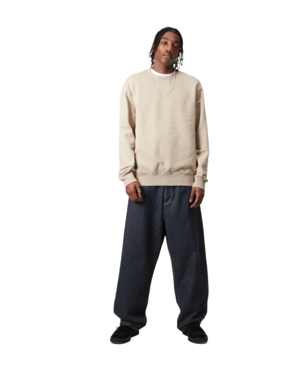 Person wearing a beige sweater and dark pants on a white background