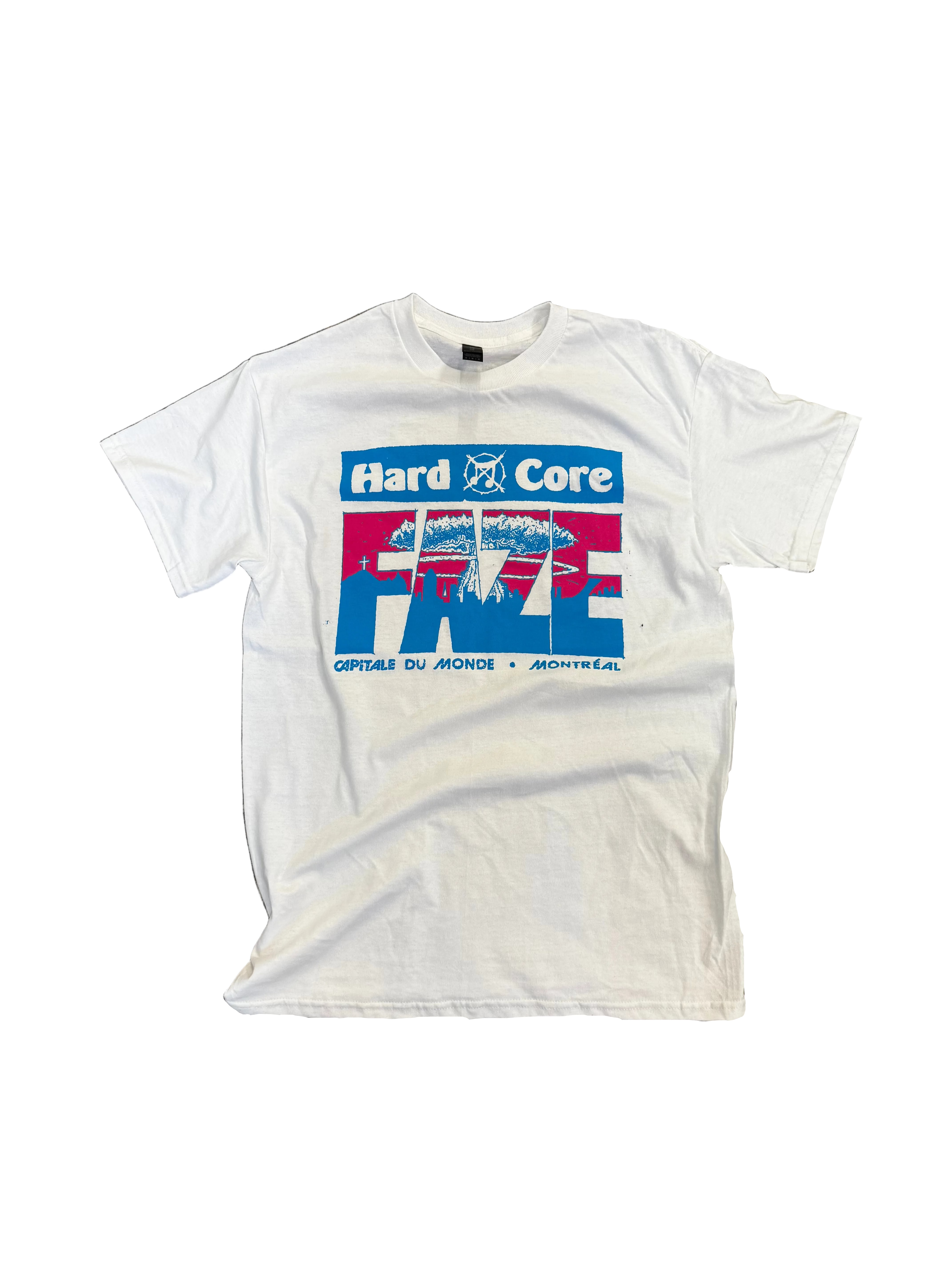 A white short-sleeve graphic t-shirt laid flat on a textured concrete floor. The shirt features a prominent front graphic with the text 'Hard Core' in a blue banner above a red, white, and blue graphic design with the word 'FBI' in stylized letters.