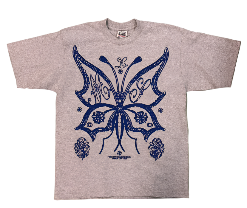Gray t-shirt with a blue butterfly design on a tiled floor